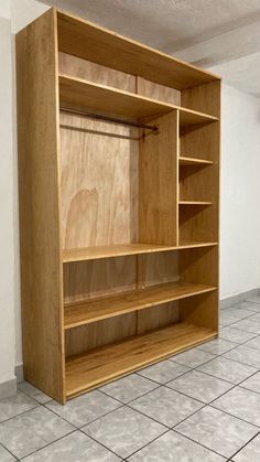 an empty wooden bookcase sitting on top of a tiled floor