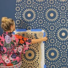 a woman painting a wall with blue and white designs