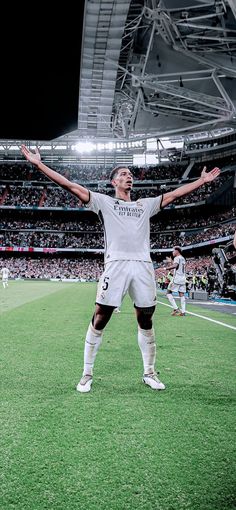 a man standing on top of a soccer field holding his arms up in the air