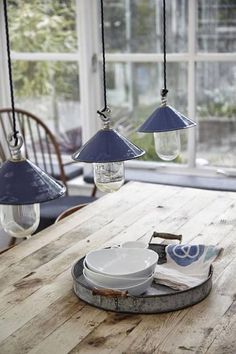 a wooden table topped with plates and hanging lights