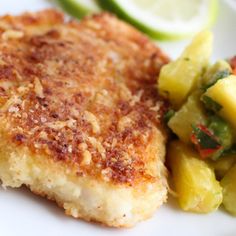 some food is on a white plate next to a lemon wedge and green pepper garnish