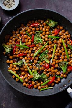 a pan filled with chickpeas and broccoli on top of a table