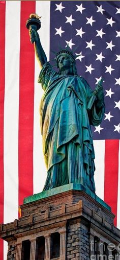 the statue of liberty stands in front of an american flag