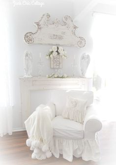 a white chair sitting next to a fireplace in a living room with flowers on the mantle