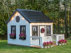 Wooden Playhouse Blacbird with a round top window, black flower boxes with pink flowers and black roof decorated with flights by WholeWoodPlayhouses 8x8 Playhouse, Metal Terrace, Wooden Outdoor Playhouse, Playhouse Interior, Luxury Playhouses, Wooden Flower Boxes, Playhouse Kits, Kids Playhouse Outdoors, Wood Playhouse