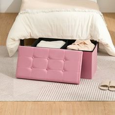 a pink foot stool sitting on top of a wooden floor next to a white bed