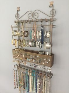 a wall mounted jewelry rack with lots of bracelets and rings hanging from it's sides