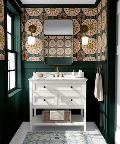 a white sink sitting under a mirror next to a green wall covered in floral wallpaper