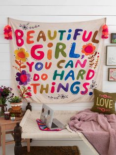 a room with a bed and a wall hanging on the wall that says beautiful girl you can do hard things