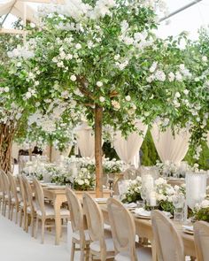 an outdoor wedding with white flowers and greenery on the tables, along with tall centerpieces