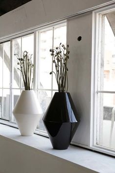 two black and white vases sitting on a window sill