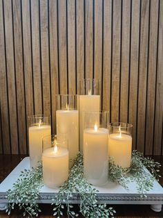 candles are arranged on a tray with greenery