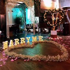 a heart - shaped sign that says marry me on the floor in front of flowers and candles