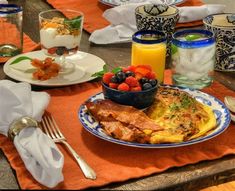 a table topped with plates of food and glasses of orange juice on top of it