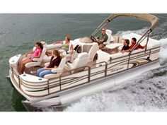 a group of people riding on the back of a white pontoon boat in the water