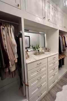 a walk in closet with white cabinets and drawers