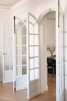 an open door leading to another room with white walls and wood flooring on the other side