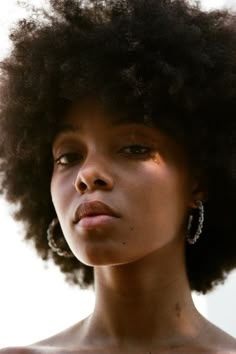 a close up of a person with an afro haircut and large earrings on her head