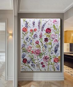 a painting on the wall in a room with wood flooring and white walls is decorated with flowers