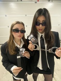 two women dressed in black and white holding up some kind of pair of scissors with their hands