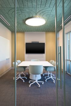 an office meeting room with a flat screen tv on the wall and chairs around it