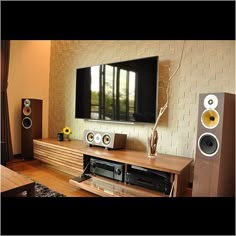 an entertainment center with speakers and a large television mounted on the wall in front of it