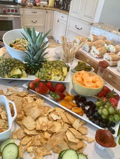 a table topped with lots of different types of snacks and fruit on top of it