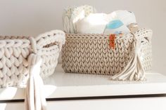 a basket sitting on top of a white dresser next to a baby crochet bag