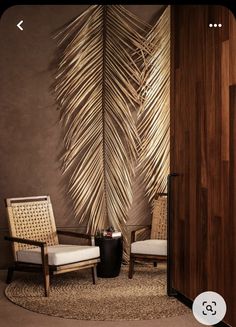 two chairs and a table in front of a wall with a palm leaf design on it