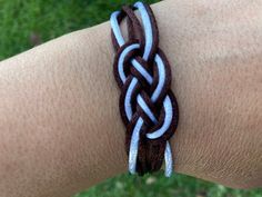 a close up of a person's arm wearing a bracelet with two braids on it