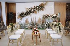 a room filled with lots of chairs covered in flowers and greenery next to a wall