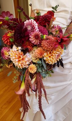 a bride holding a bouquet of flowers in her hand on the floor with wood floors