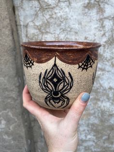 a hand holding a cup with spider web designs on it