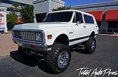 a large white truck parked in front of a store with big tires on it's tires