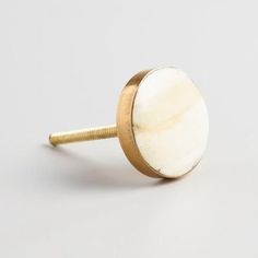 a white and gold colored knob on a white surface with a screw in the middle