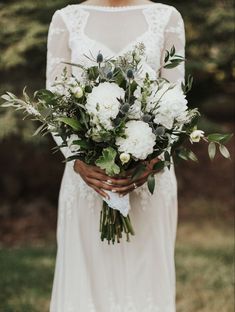 a woman holding a bouquet of white flowers