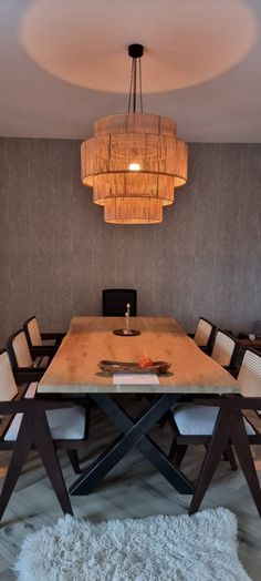 a dining room table with chairs and a chandelier hanging from it's ceiling