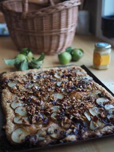 an apple and walnut tart sitting on top of a table next to some fruit