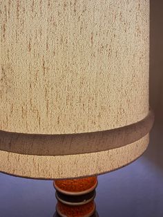 a lamp that is on top of a wooden base and has a brown fabric shade over it