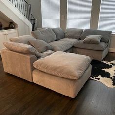 a living room with a large sectional couch and cow hide rug on the hardwood floor