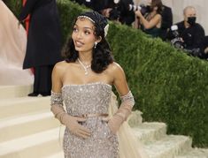 a woman in a gown and gloves is standing on the stairs with cameras around her