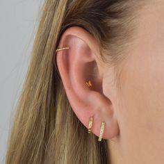 a close up of a woman's ear with two small gold hoops on it