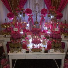 a table topped with lots of desserts covered in pink and gold