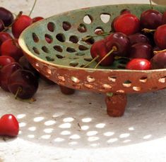 a bowl filled with cherries sitting on top of a table