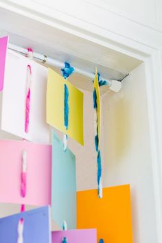 colorful paper hanging from the ceiling in front of a white wall with blue and yellow streamers