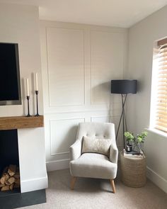 a living room with a fireplace, chair and television on the wall next to it