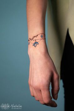 a woman's hand with a blue flower tattoo on her left wrist and the other arm