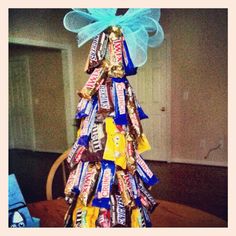 a christmas tree made out of candy bars on top of a wooden table with a blue bow