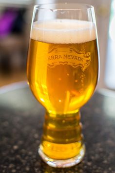 a glass filled with beer sitting on top of a table