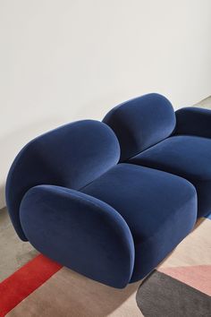 a large blue couch sitting on top of a colorful rug in front of a white wall